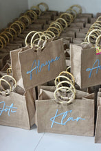 Afbeelding in Gallery-weergave laden, Travellers Hat Boutique personalized jute totes with bamboo handles and blue script names
