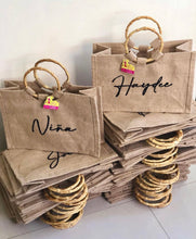Afbeelding in Gallery-weergave laden, Stack of personalized jute tote bag with bamboo handle featuring custom names in black script