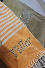 Load image into Gallery viewer, Personalized beach towel with Villar embroidery in orange and beige striped design with fringed edges