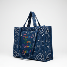 Load image into Gallery viewer, A navy blue tote bag with a white paisley bandana print and colorful embroidered text reading 'Travel Now, Pulubi Later!' on the front, shown against a plain white background.
