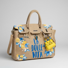 Load image into Gallery viewer, Beige handbag with floral designs and 'La Dolce Vita' text on a light gray background
