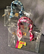 Charger l&#39;image dans la galerie, Travellers Hat Boutique clear PVC tote bag with colorful patterned handles and gold-tone hardware
