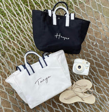 Lataa kuva Galleria-katseluun, Embroidered boat tote bag in black and white with personalized names displayed on a net background
