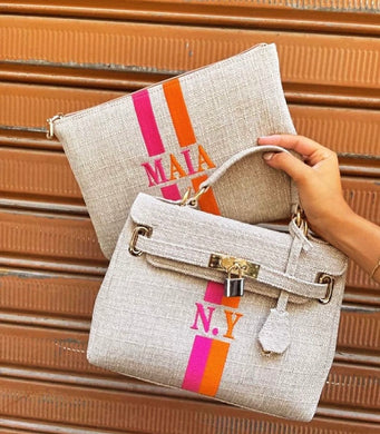 Custom O'Kelly tote bag in beige with orange and pink stripes and gold hardware held by hand