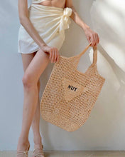 Carregar imagem no visualizador da galeria, Woman holding handmade raffia bucket bag tote bag with NUT print in neutral tones
