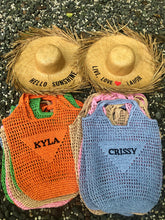 Carregar imagem no visualizador da galeria, Handmade raffia bucket bag in orange and blue with personalized names on a natural textured background
