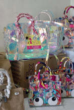 Carregar imagem no visualizador da galeria, Holographic clear tote bag from Travellers Hat Boutique with pink wrapped handles on display
