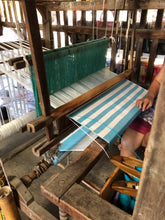 Load image into Gallery viewer, Handwoven striped blue and white personalized beach towel being crafted on a traditional loom
