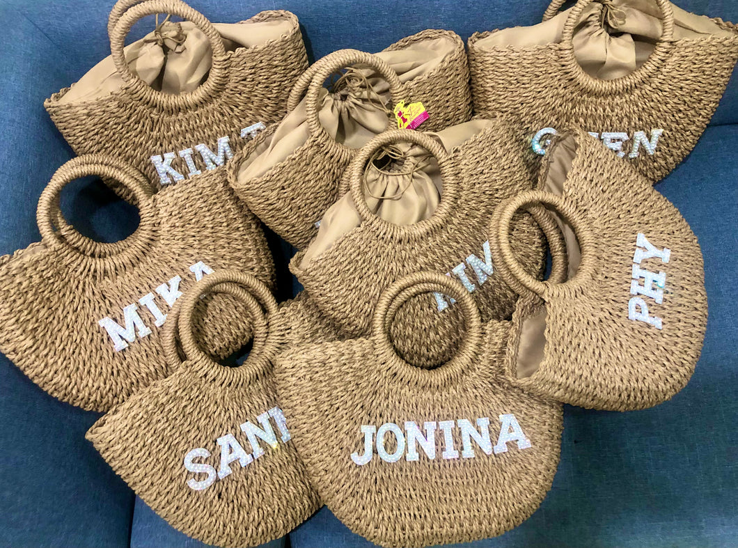 Personalized straw beach bag totes with round handles and custom white name embroidery by Travellers Hat Boutique
