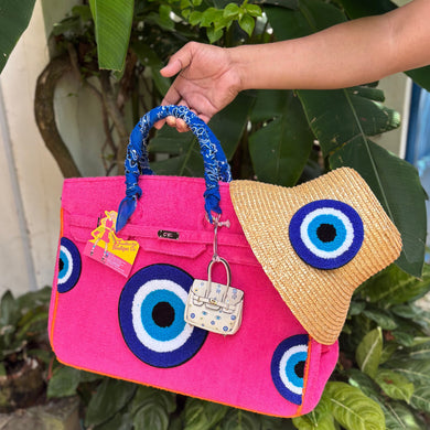 Pink terry beach bag with blue circular patterns and blue wrapped handles held outdoors