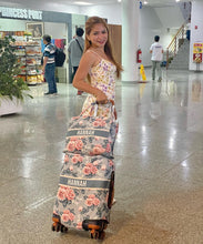 Load image into Gallery viewer, Travel luggage cover with name Hannah in floral pattern on rolling suitcase held by woman
