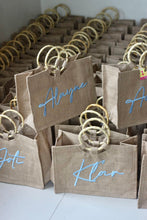 Load image into Gallery viewer, Travellers Hat Boutique personalized jute totes with bamboo handles and blue script names
