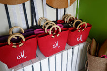 Load image into Gallery viewer, Personalized abaca tote bag in red with wooden handles and embroidered initial M displayed at Travellers Hat Boutique
