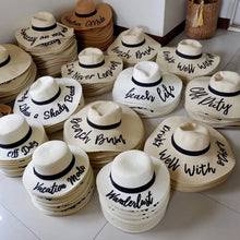 Cargar imagen en el visor de la galería, Wholesale floppy sun hats in beige with black ribbon and custom phrases at Travellers Hat Boutique
