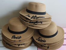 Carregar imagem no visualizador da galeria, Custom embroidered round hats in tan with black bands stacked, featuring personalized names by Travellers Hat Boutique
