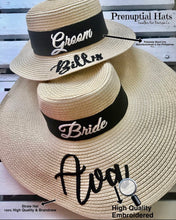 Cargar imagen en el visor de la galería, Custom prenuptial hat set featuring groom and bride straw hats with black bands and embroidered names
