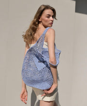 Carregar imagem no visualizador da galeria, Handmade raffia bucket bag in light blue carried by woman wearing white dress from Travellers Hat Boutique
