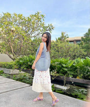 Carregar imagem no visualizador da galeria, Woman carrying handmade raffia bucket bag by Travellers Hat Boutique outdoors in floral dress
