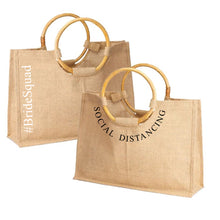 Load image into Gallery viewer, Natural jute totes with wooden round handles featuring BrideSquad and Social Distancing text from Travellers Hat Boutique
