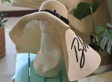 Lade das Bild in den Galerie-Viewer, Oversized straw sun hat with wide brim and black ribbon detail displayed on mannequin head
