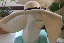 Lade das Bild in den Galerie-Viewer, Oversized straw sun hat with wide brim and black band displayed on a white mannequin head
