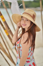 Carregar imagem no visualizador da galeria, Woman wearing a panama wheat hat from Travellers Hat Boutique with a wide brim and brown band
