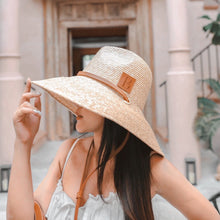 Carregar imagem no visualizador da galeria, Woman wearing a panama wheat hat with wide brim and leather band from Travellers Hat Boutique

