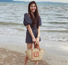 Lade das Bild in den Galerie-Viewer, Woman holding seagrass basket handbag with leather handles on the beach by the ocean waves
