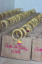 Load image into Gallery viewer, Jute tote bags with bamboo handles featuring pink embroidery for a birthday event by Travellers Hat Boutique
