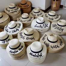 Load image into Gallery viewer, Wholesale floppy sun hats in beige with black ribbon and custom phrases at Travellers Hat Boutique
